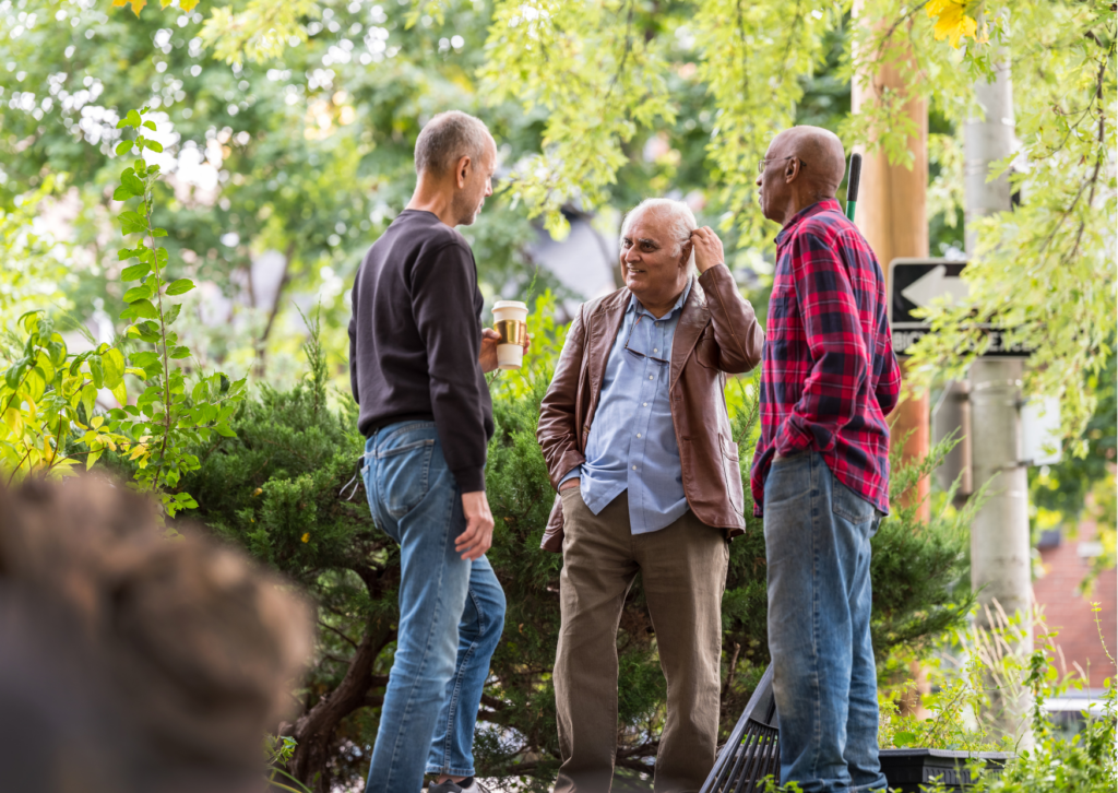 Tre menn rydder i hagen og snakker sammen