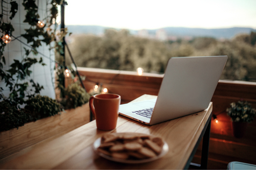 laptop på et terrassebord med utsikt over trær